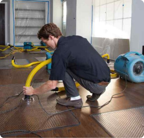 echnician using specialized floor drying equipment for environmental remediation services provided by Peak Fire & Flood in Denver and Colorado's Front Range.