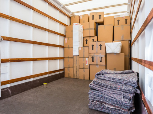 Moving truck loaded with packed boxes and blankets, symbolizing content restoration services for fire, water, and sewage-damaged personal property