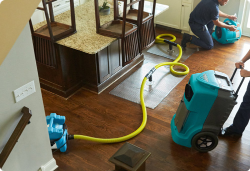 Peak Fire and Flood team performing water damage cleanup and mitigation services in a residential kitchen, using advanced drying and dehumidifying equipment to prevent mold growth and restore the property.